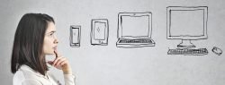 Symbolbild Frau denkt über verschiedene Ausgabegeräte wie Tablet, Smartphone oder Computer nach.
