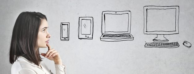 Symbolbild Frau denkt über verschiedene Ausgabegeräte wie Tablet, Smartphone oder Computer nach.