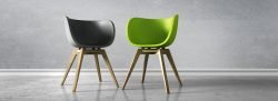 Ein schwarzer und ein grüner Stuhl stehen vor einer Betonwand