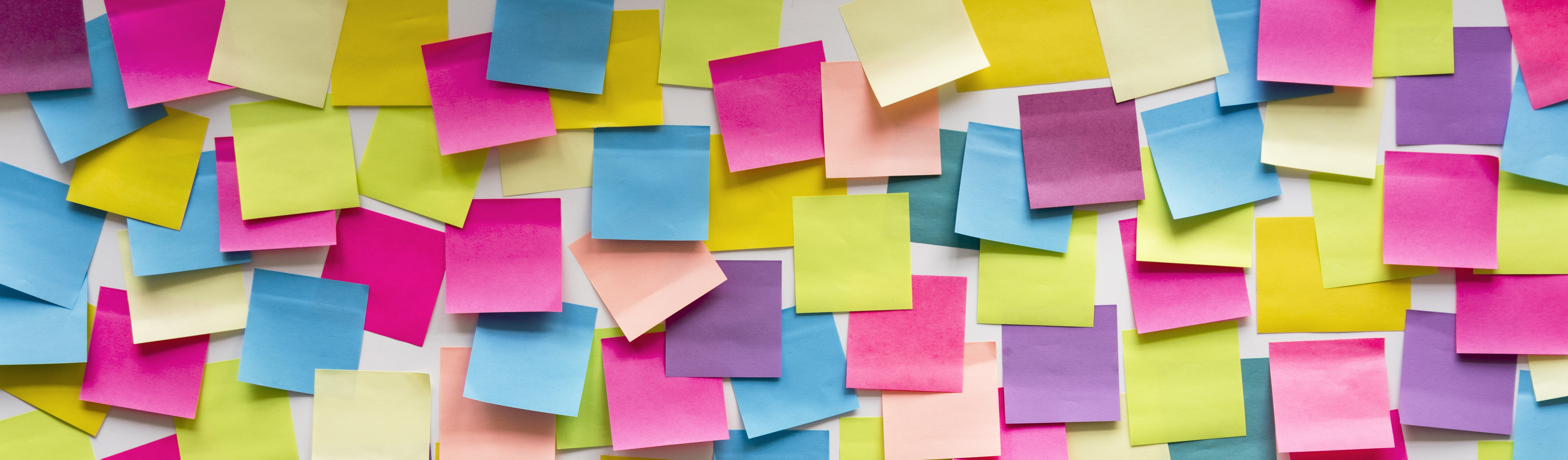 Eine Wand an der viele bunte Post-it-Klebezettel kleben