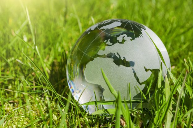 Eine Glasweltkugel liegt im Gras - Nachhaltige Entwicklung